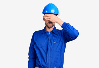 Young handsome man wearing worker uniform and hardhat clueless and confused with open arms, no idea concept.