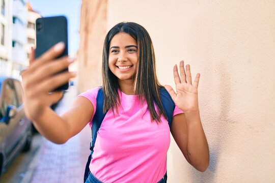 Young latin student girl doing video call using smartphone at university campus.