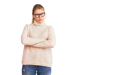 Young beautiful blonde woman wearing turtleneck sweater and glasses skeptic and nervous, disapproving expression on face with crossed arms. negative person.