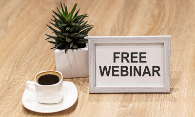 Frame with text Free webinar. Nearby is a flower and a cup of coffee on a wooden table. Business concept.