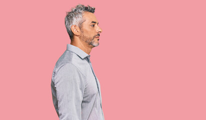 Middle age grey-haired man wearing casual clothes looking to side, relax profile pose with natural face with confident smile.