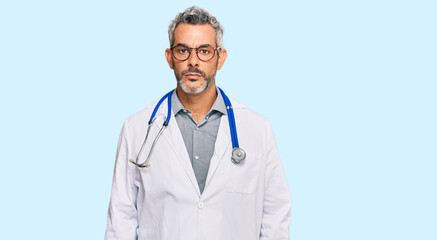 Middle age grey-haired man wearing doctor uniform and stethoscope with serious expression on face....
