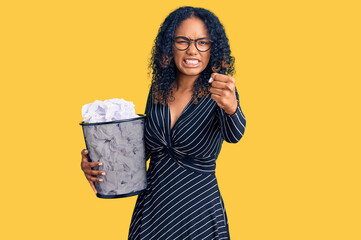 Young african american woman holding paper bin full of crumpled papers annoyed and frustrated shouting with anger, yelling crazy with anger and hand raised