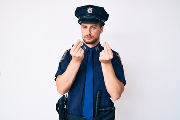Young caucasian man wearing police uniform doing money gesture with hands, asking for salary payment, millionaire business