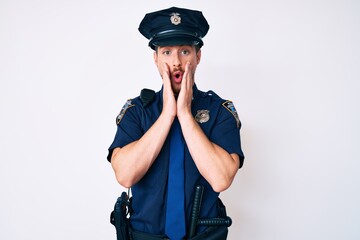 Young caucasian man wearing police uniform afraid and shocked, surprise and amazed expression with hands on face