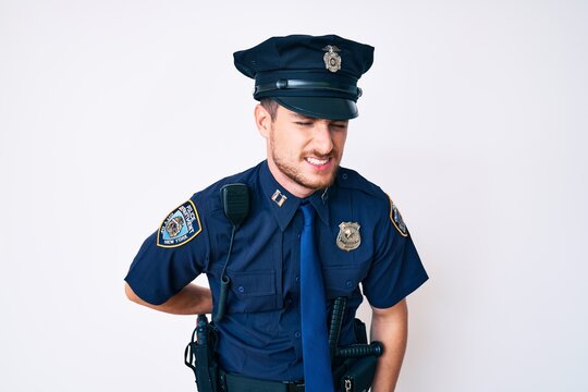 Young caucasian man wearing police uniform suffering of backache, touching back with hand, muscular pain