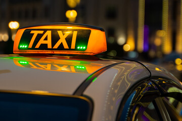 Illuminated orange taxi sign on a white car. Luminous scoreboard.