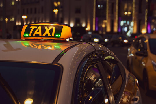 Illuminated orange taxi sign on a white car. Luminous scoreboard.