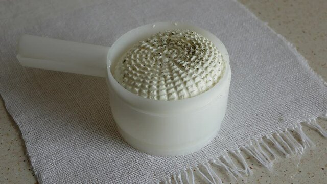 Fresh homemade cottage cheese in a cheese making mold, Cheese maker puts the herbes de Provence over the cheese 