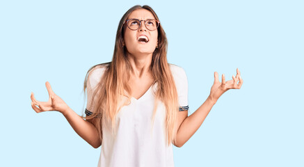 Fototapeta na wymiar Beautiful caucasian woman wearing casual clothes and glasses screaming proud, celebrating victory and success very excited with raised arm