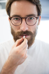 Man in a white t-shirt taking a pill, a tablet, close up.