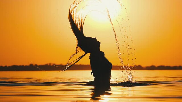 Silhouette of Woman Flipping Her Long Hair Back in Water. Slow Motion 240 fps