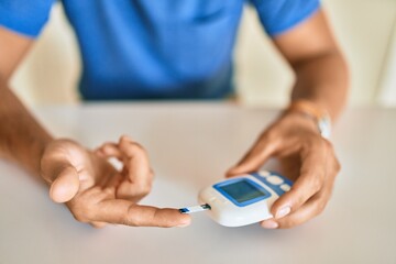Young hispanic diabetic man measuring glucose level at home