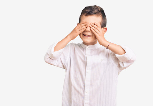 Cute blond kid wearing elegant shirt covering eyes with hands smiling cheerful and funny. blind concept.