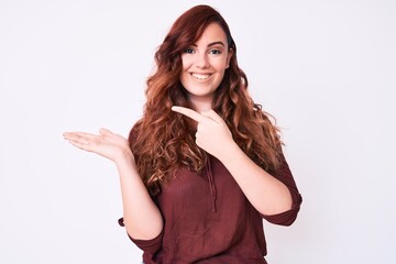 Young beautiful woman wearing casual clothes amazed and smiling to the camera while presenting with hand and pointing with finger.