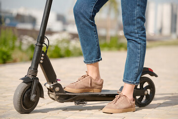 Obraz premium Side view of legs of young businesswoman in beige suede shoes and blue jeans
