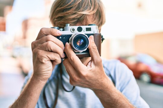 Young irish photographer man using vintage camera at street of city.