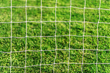 White soccer goal net on grass background close-up. © Denis Rozhnovsky