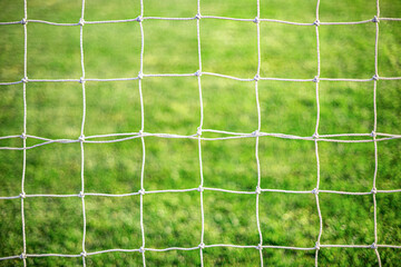 White soccer goal net on grass background close-up.