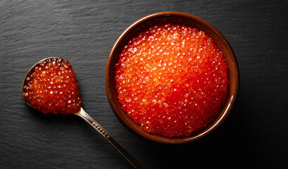 Red caviar in pot on stone plate.