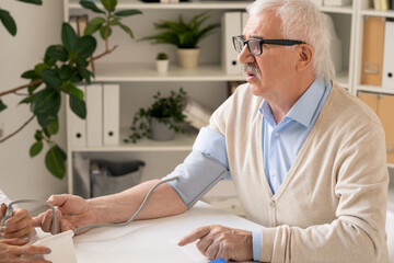 Aged man asking for medical advice during procedure of measuring blood pressure