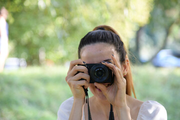 Schöne Frau fotografiert mit professioneller Kamera. Frau geht im Park spazieren.