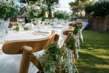 Close-up of wedding chairs with decorated with white ribbons and flowers