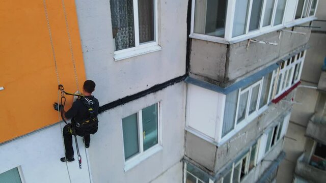 Painting and decorating buildings. Worker on a construction site of a high-rise building. Dangerous work in high-altitude engineering design. Iron and concrete.