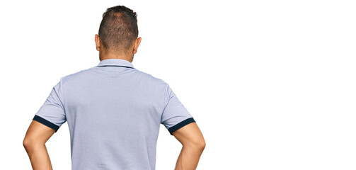 Handsome man with beard wearing casual clothes standing backwards looking away with arms on body