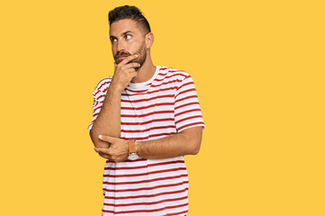 Handsome man with beard wearing striped tshirt serious face thinking about question with hand on...