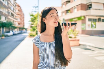 Young chinese woman smiling happy talking on the smartphone at street of city.