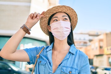 Young chinese tourist woman wearing medical mask walking at street of city.