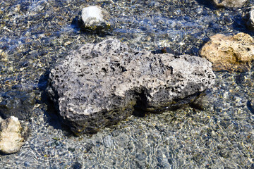Multi-colored stones on the shores of a shallow and very salty lake. The boulders are covered with a layer of crystalline salt.