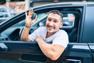 Young hispanic man smiling happy holding key of new car
