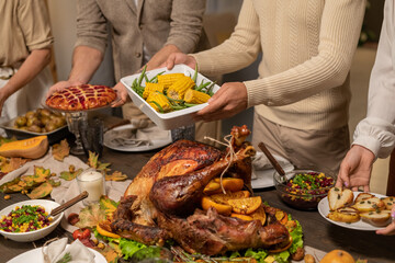 Four members of family putting plates and bowls with homemade food on table