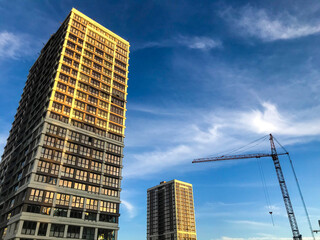 Fototapeta premium brown and white multi-storey building in the city center. there is a small building next to the high-rise building. transition from house to house along the bridge. against the blue sky