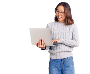 Young beautiful chinese girl wearing glasses holding laptop looking positive and happy standing and smiling with a confident smile showing teeth