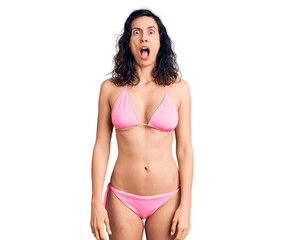 Fototapeta premium Young beautiful hispanic woman wearing bikini afraid and shocked with surprise and amazed expression, fear and excited face.