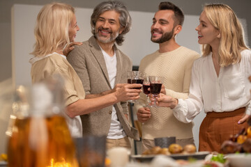 Happy young couple and smiling mature man looking at blond female toasting