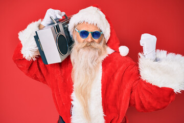 Old senior man wearing santa claus costume and boombox annoyed and frustrated shouting with anger, yelling crazy with anger and hand raised