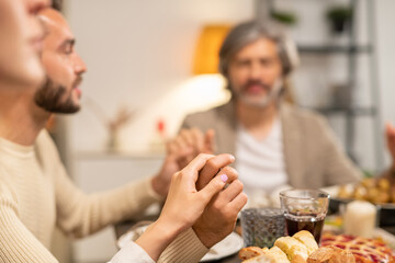 Young woman, her husband and father holding by hands and keeping eyes closed