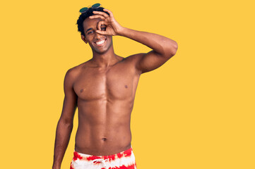 Fototapeta premium African handsome man wearing swimsuit and sunglasses doing ok gesture with hand smiling, eye looking through fingers with happy face.