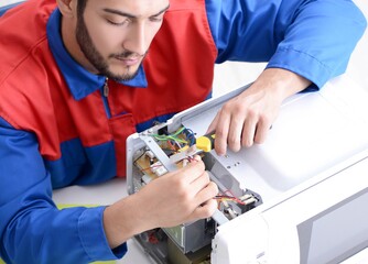 Young repairman fixing and repairing microwave oven