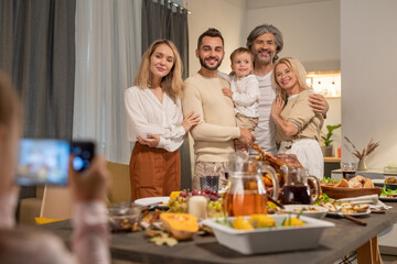 Cheerful and affectionate three generation family standing by festive table