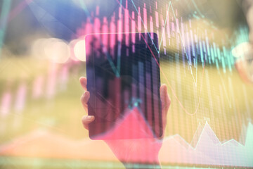 Naklejka premium Double exposure of forex chart sketch hologram and woman holding and using a mobile device. Financial market concept.