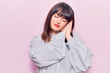Obraz premium Young plus size woman wearing casual clothes sleeping tired dreaming and posing with hands together while smiling with closed eyes.