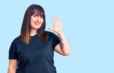 Young plus size woman wearing casual clothes showing and pointing up with fingers number five while smiling confident and happy.