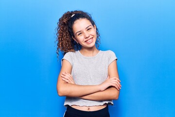 Beautiful kid girl with curly hair wearing casual clothes happy face smiling with crossed arms looking at the camera. positive person.