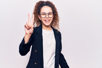 Beautiful kid girl with curly hair wearing business clothes and glasses smiling with happy face winking at the camera doing victory sign. number two.