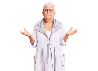 Senior beautiful woman with blue eyes and grey hair wearing casual clothes and glasses clueless and confused expression with arms and hands raised. doubt concept.